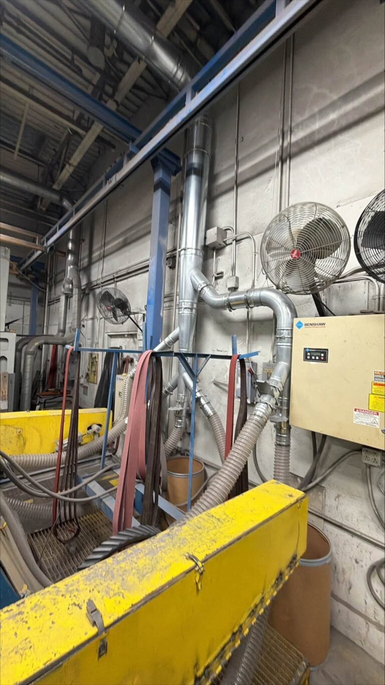 Overhead main ductwork and individual drops serving workstations throughout the production area.